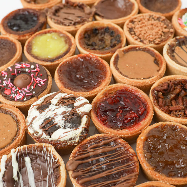Close-up of a flaky butter tart with a glossy, caramel-like filling in a pastry shell on a rustic wooden surface