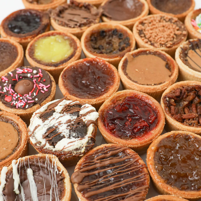 Close-up of a flaky butter tart with a glossy, caramel-like filling in a pastry shell on a rustic wooden surface