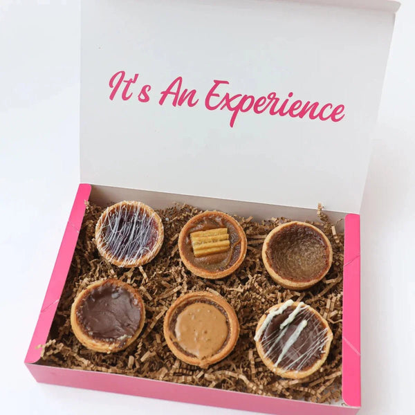 Assorted cookie boxes, brownies, and mini pastries arranged for a corporate thank-you gift, highlighting shareable desserts