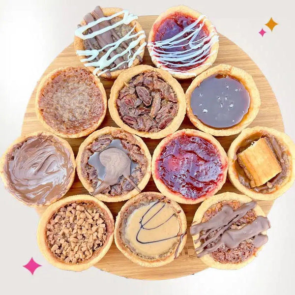 Close-up of a tray of butter tarts in flaky shells with glossy, caramel-colored filling cooling on a pastry tray