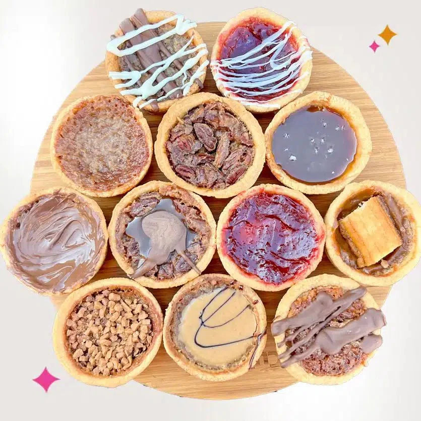 Close-up of a tray of butter tarts in flaky shells with glossy, caramel-colored filling cooling on a pastry tray
