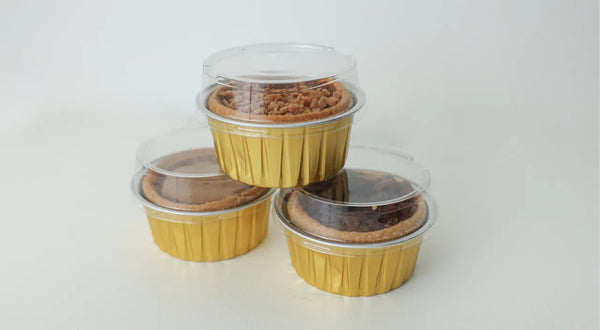 Close-up of golden butter tarts on a rustic table, hinting at wedding and event favors with simple packaging ideas in the background.