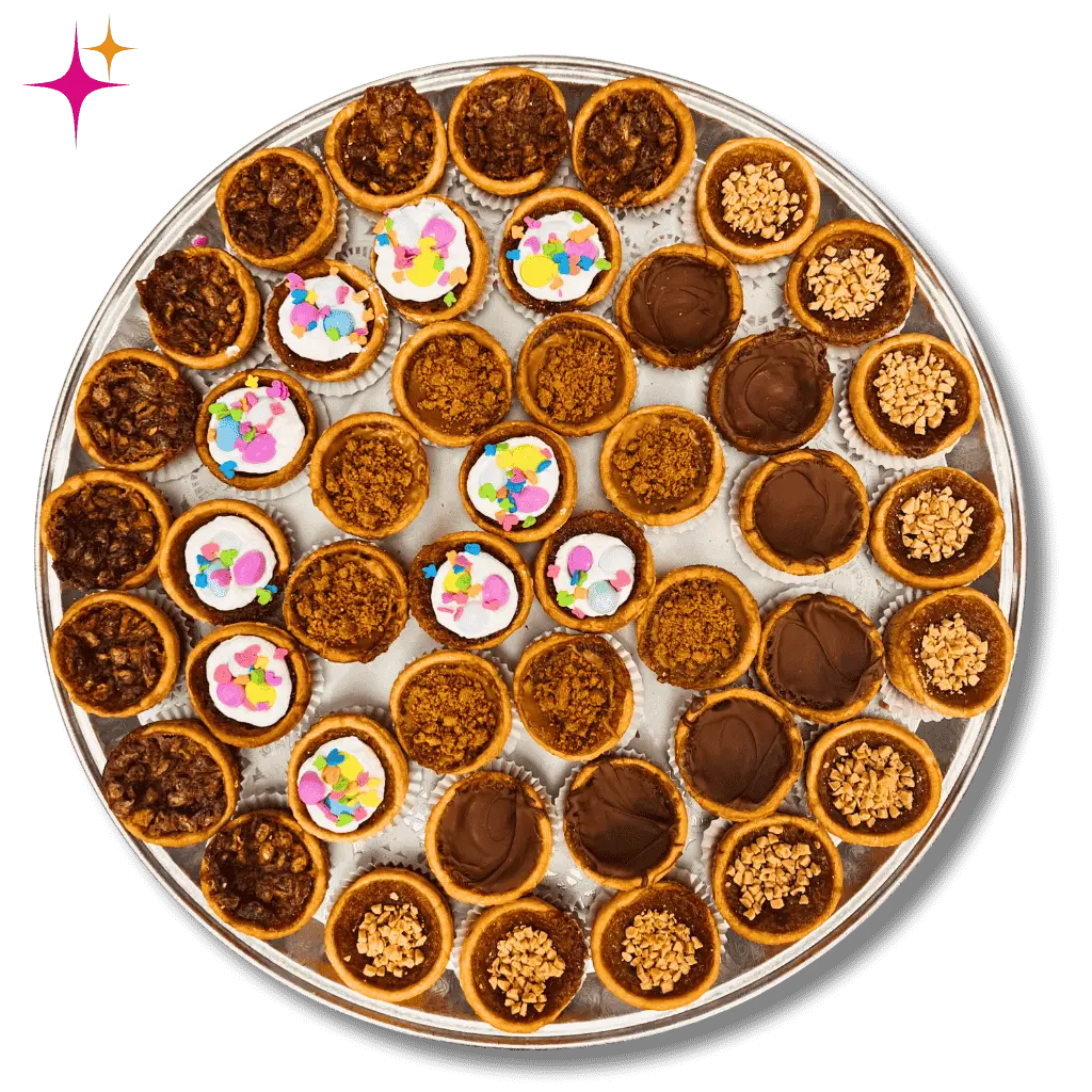 Assorted butter tart platter from Carla’s Cookie Box with flavours including classic, chocolate, toffee crumble, and sprinkle-topped tarts arranged on a silver serving tray.